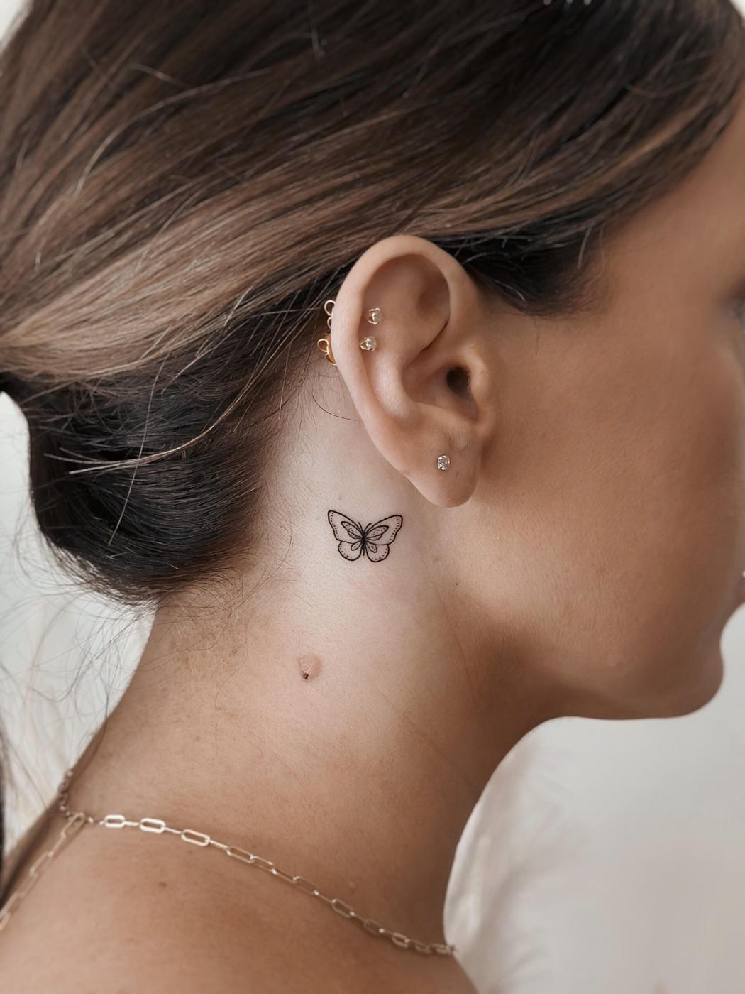 Small fine line butterfly tattoo placed behind the ear