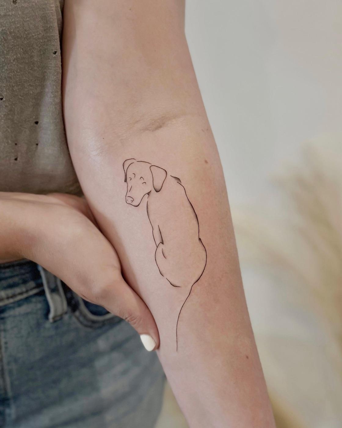 Minimal fine line dog outline tattoo on the inner arm