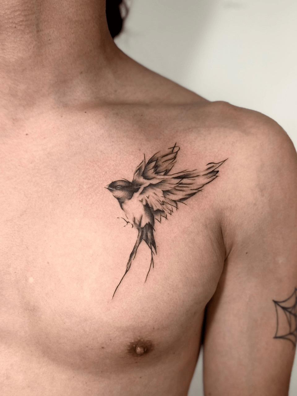 Sketch-style black and grey swallow chest tattoo