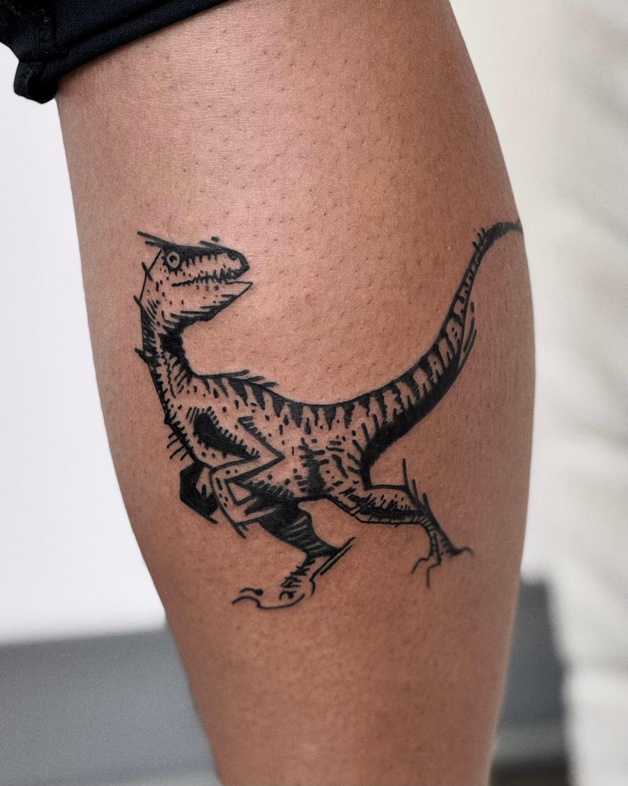 Black and grey raptor dinosaur tattoo