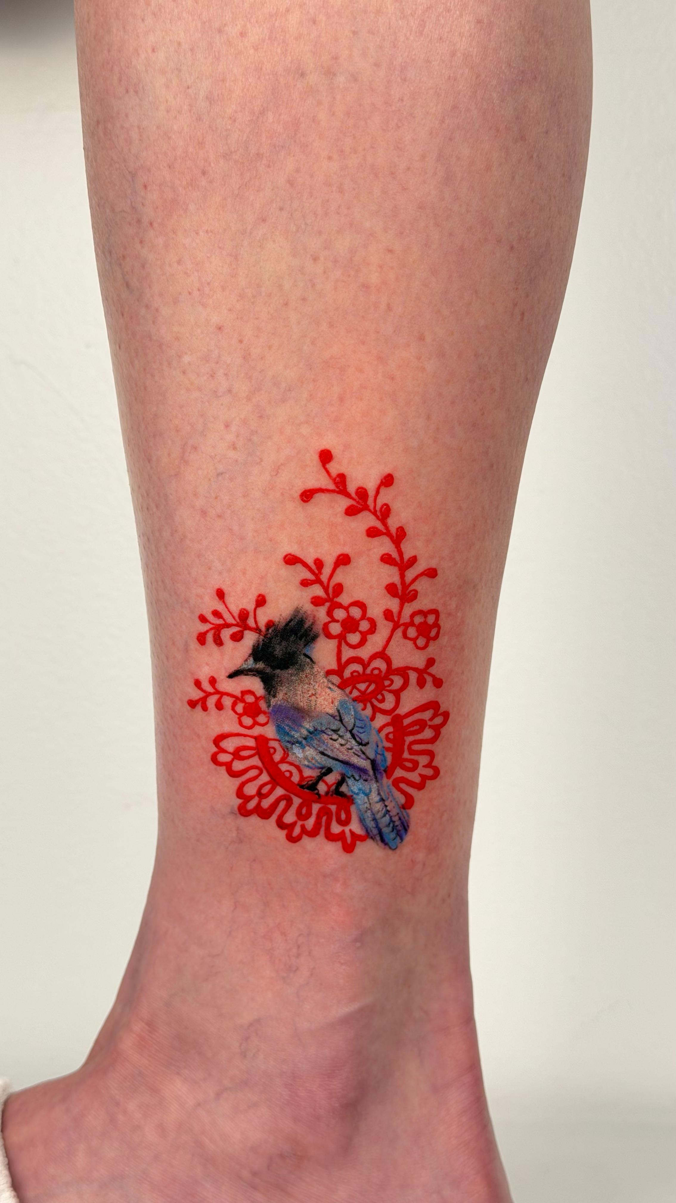 Color bird tattoo with red floral pattern