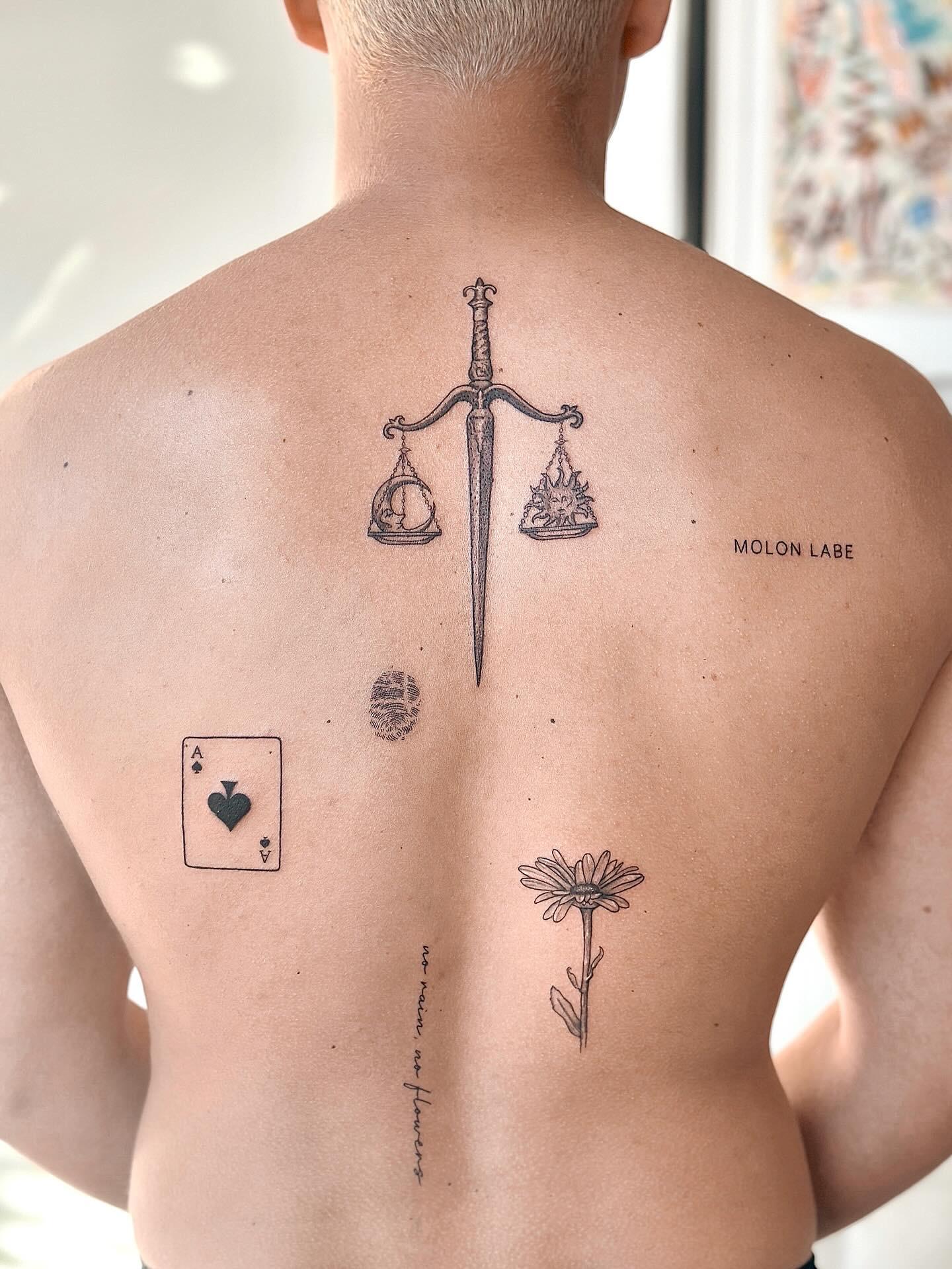 Collection of fine line tattoos across the upper back