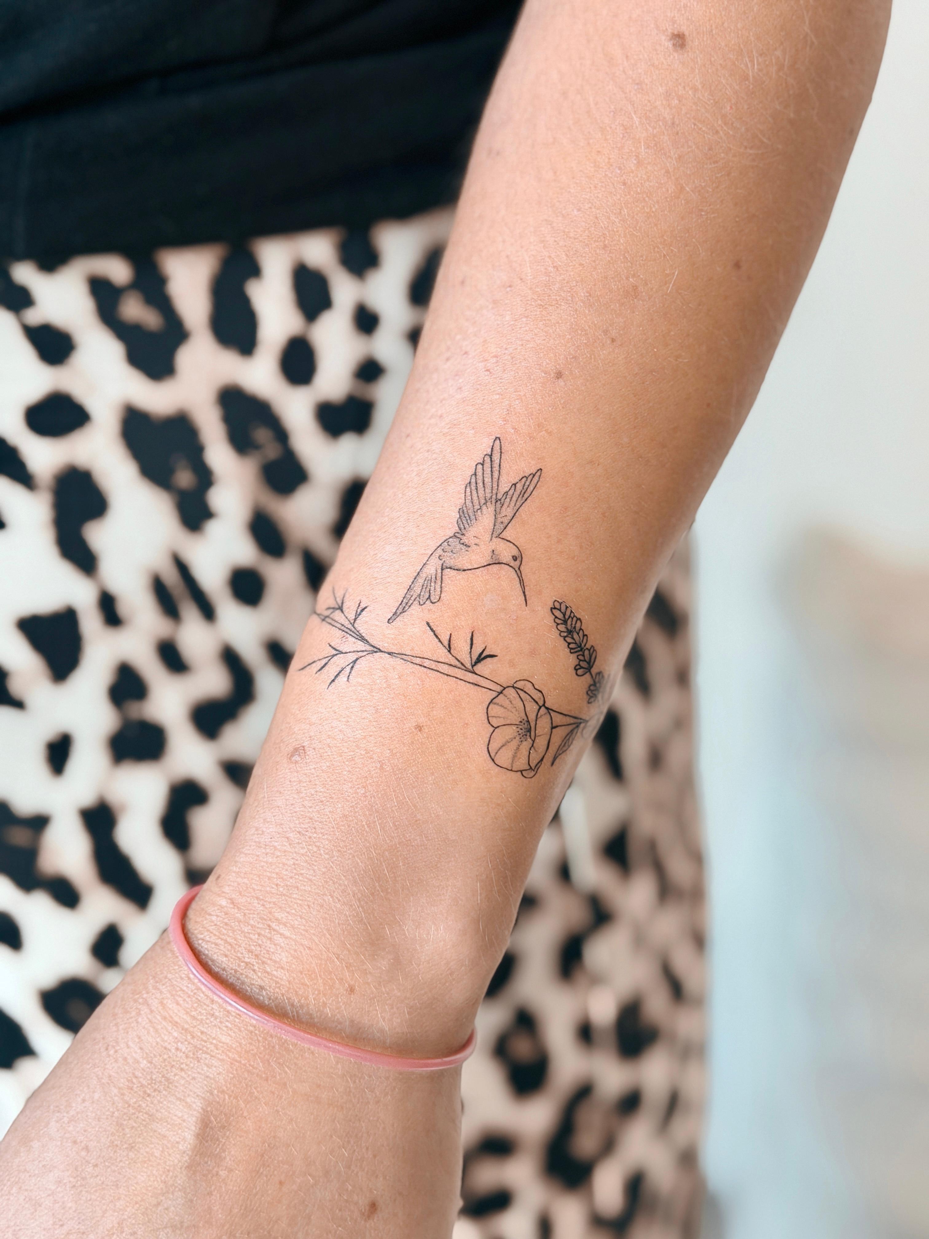 Fine line hummingbird and flower tattoo