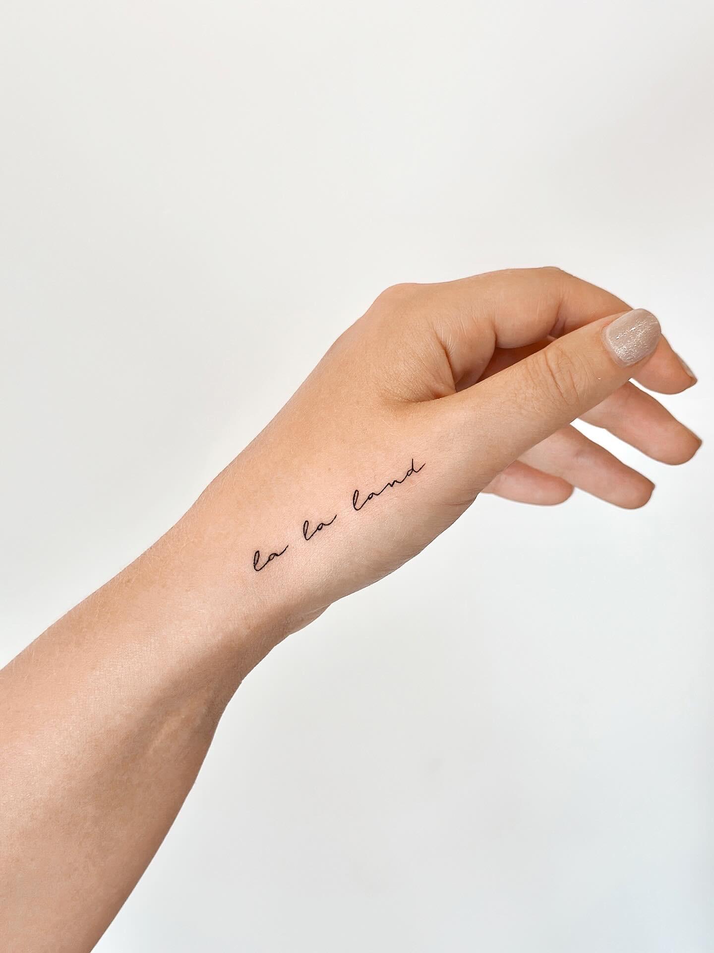 Fine line script tattoo reading la la land on the hand